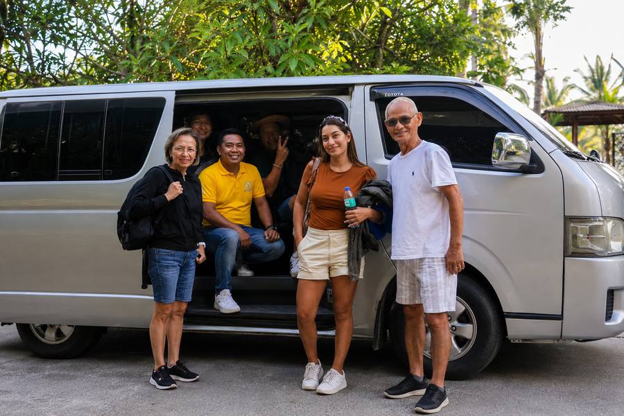 Shuttle Siargao driver with happy passenger group beside Toyota van